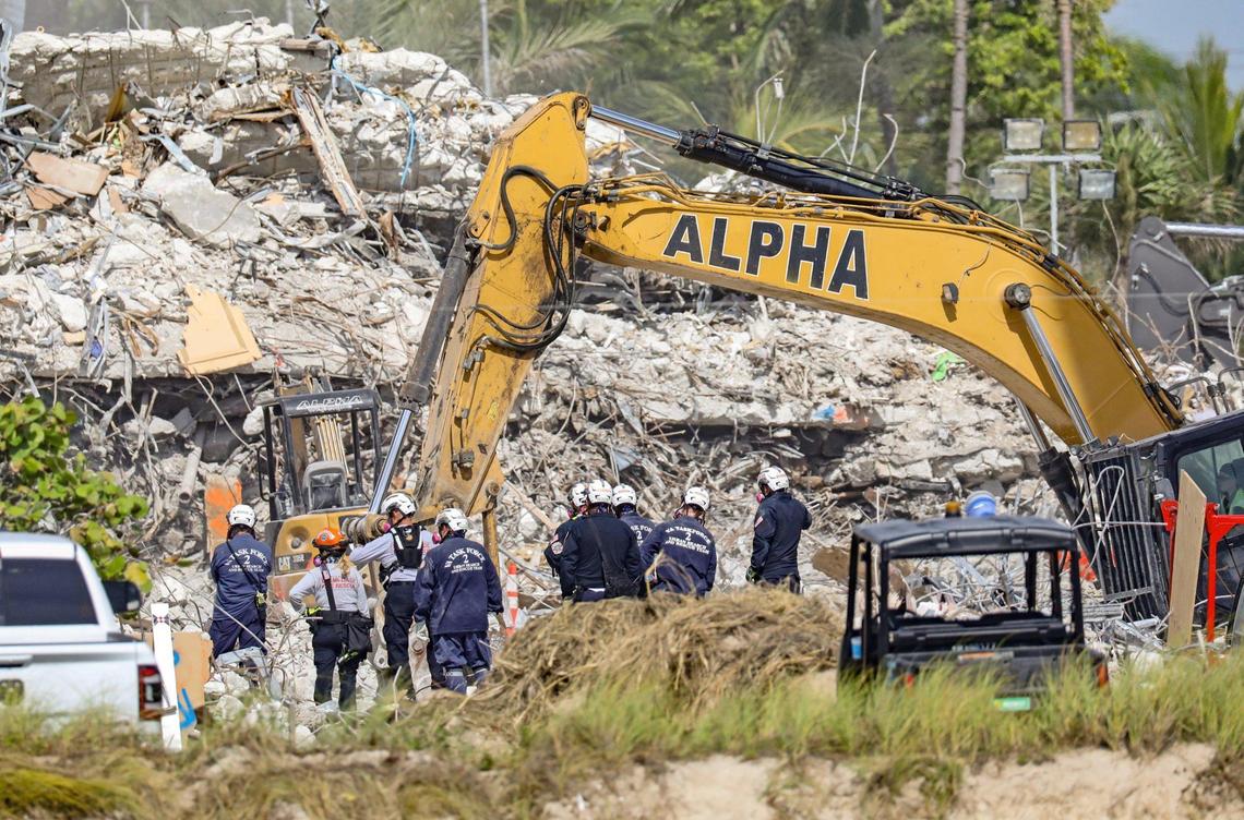 Search teams watch heavy machinery clear the debris left after the partial collapse and demolition of the 12-story oceanfront condo, Champlain Towers South. in Surfside on Friday, July 09, 2021.