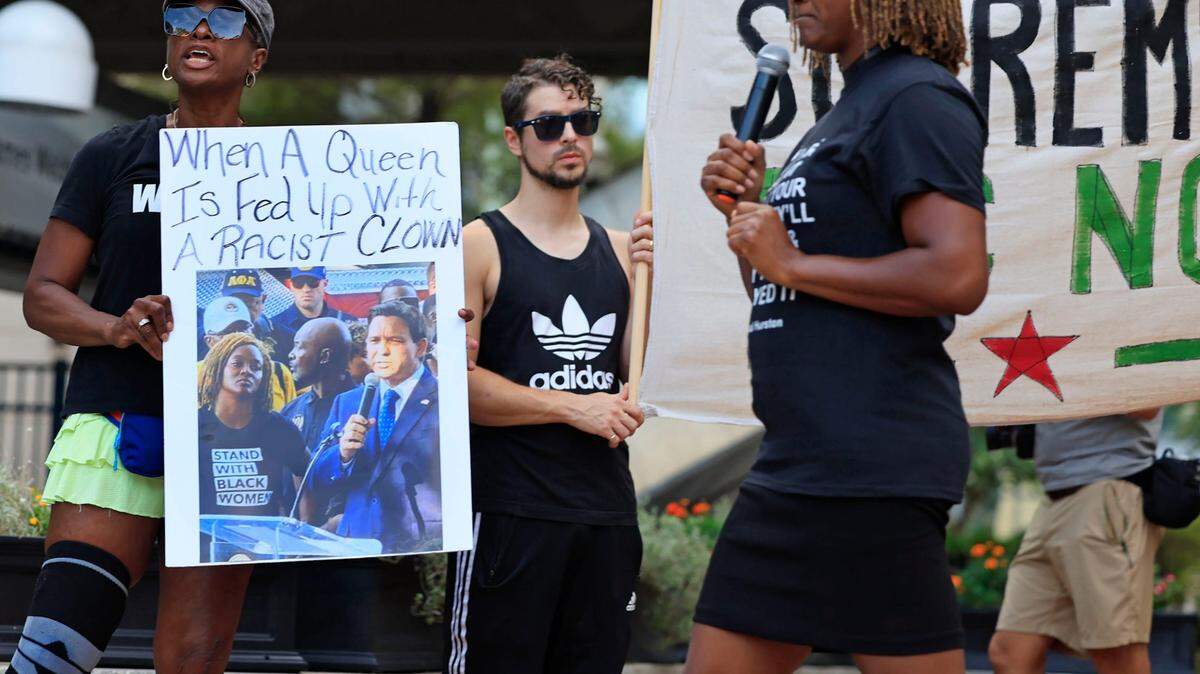 Sheila Jackson holds up a sign and photo showing a photo of Florida Rep. Angie Nixon staring down Gov. Ron DeSantis as the actual Angie Nixon passes while speaking Monday, Aug. 28, 2023 at James Weldon Johnson Park in downtown Jacksonville, Fla. In light of the recent shooting at the Dollar General, that left three African-American individuals dead, hundreds came out to rally against white supremacy.