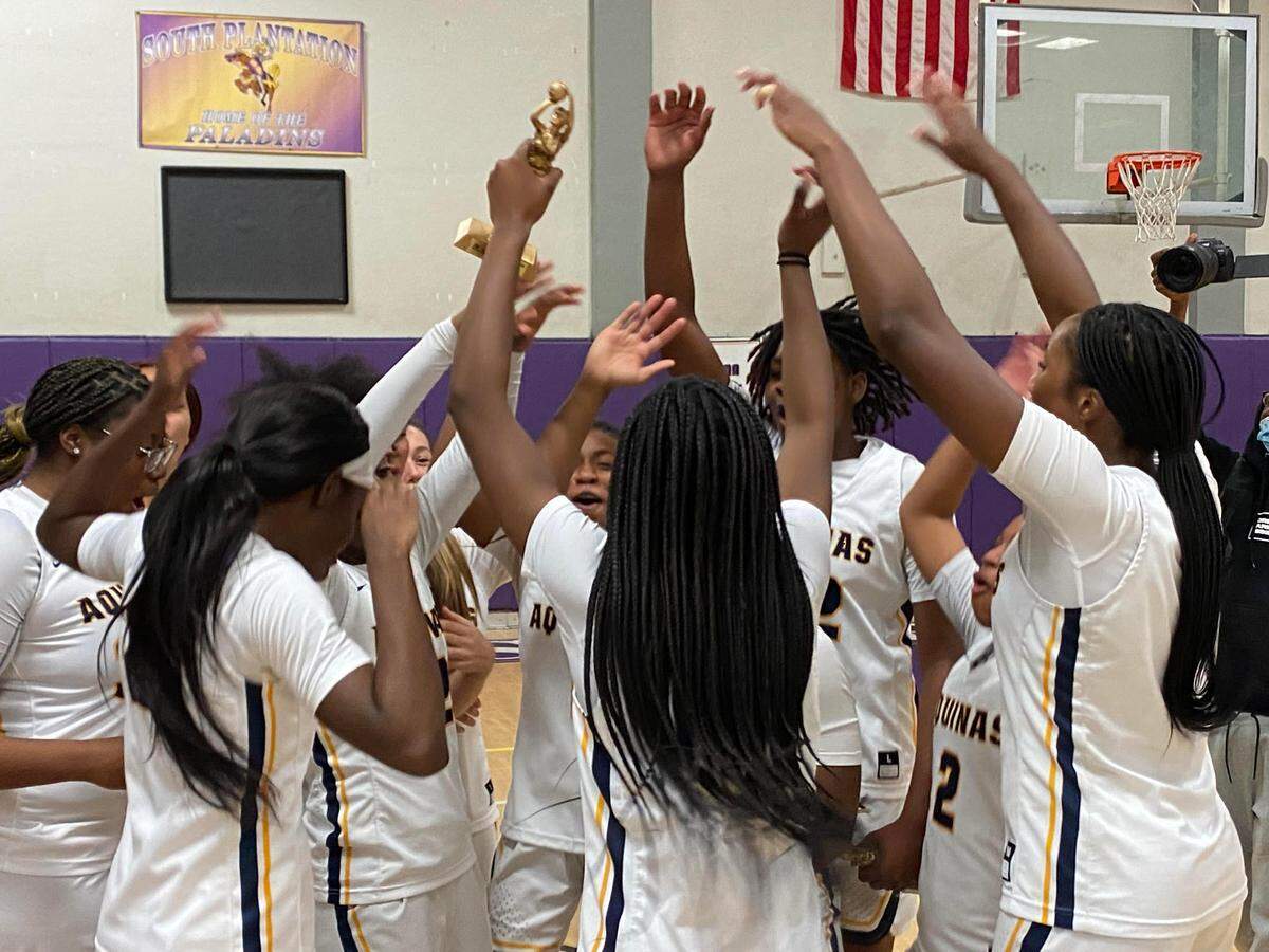St. Thomas Aquinas’ players celebrate their first BCAA Big 8 girls’ basketball tournament championship after beating Dillard 65-51 on Saturday night at South Plantation High.