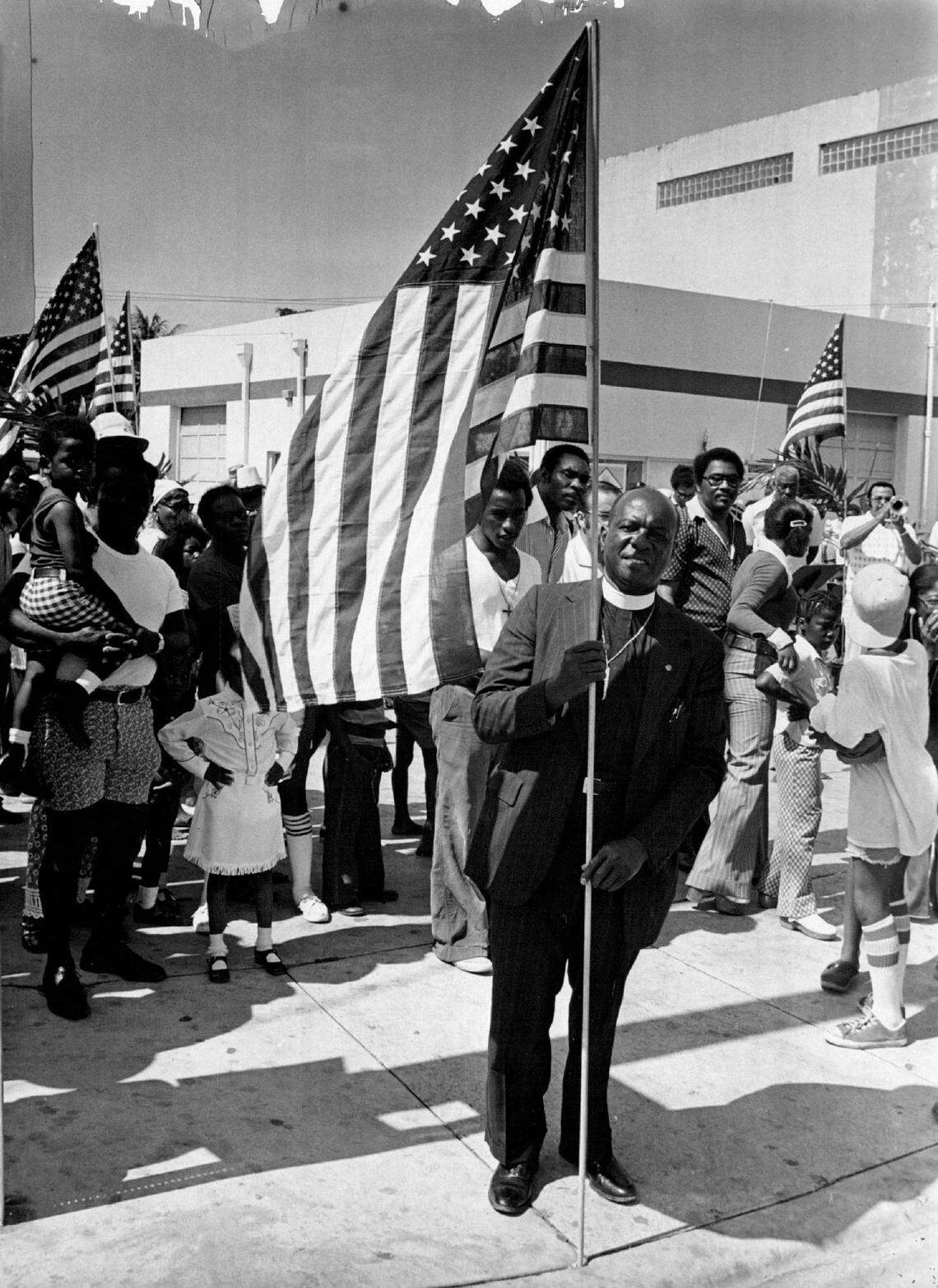 The Rev. Theodore Gibson, a Miami civil rights leader, plants a U.S. flag on one of the four corners at Douglas Road and Grand Avenue in the historically Black section of Coconut Grove during a Memorial Day ceremony in an undated file photo.