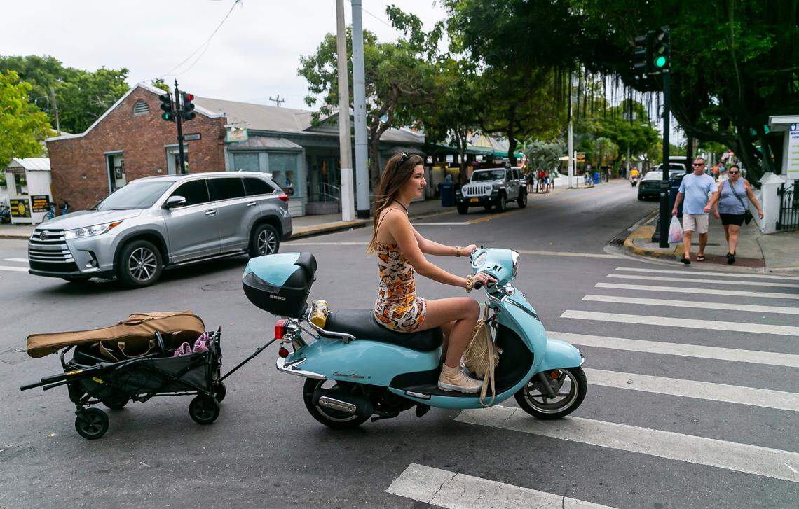Singer Elle Haley rides a scooter with her music equipment as she makes her way toward Hank’s Hair of the Dog Saloon in Key West, Florida on Sunday, December 12, 2021.
