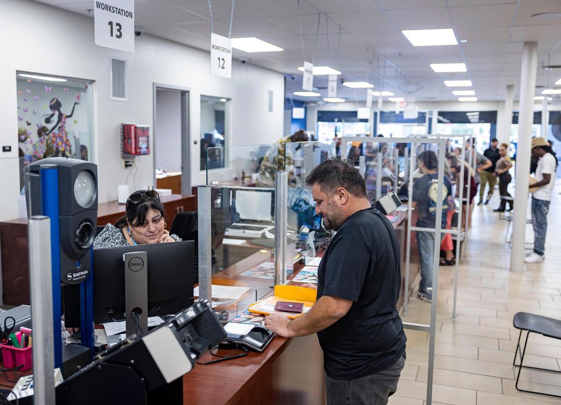 Fatih Abay, de 38 año (centro) recibe ayuda de un representante de servicio al cliente dentro de un Centro de Servicio de Vehículos Motorizados y Licencias de Conducir de Seguridad en las Carreteras y Vehículos Motorizados de Florida el miércoles 16 de abril de 2025, en Miami, Florida.