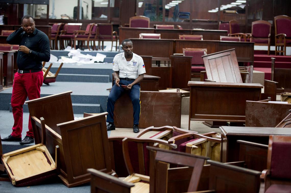 A security officer sits amid overturned tables inside Parliament after it was vandalized in Port-au-Prince, Haiti, Tuesday, Sept. 3, 2019.
