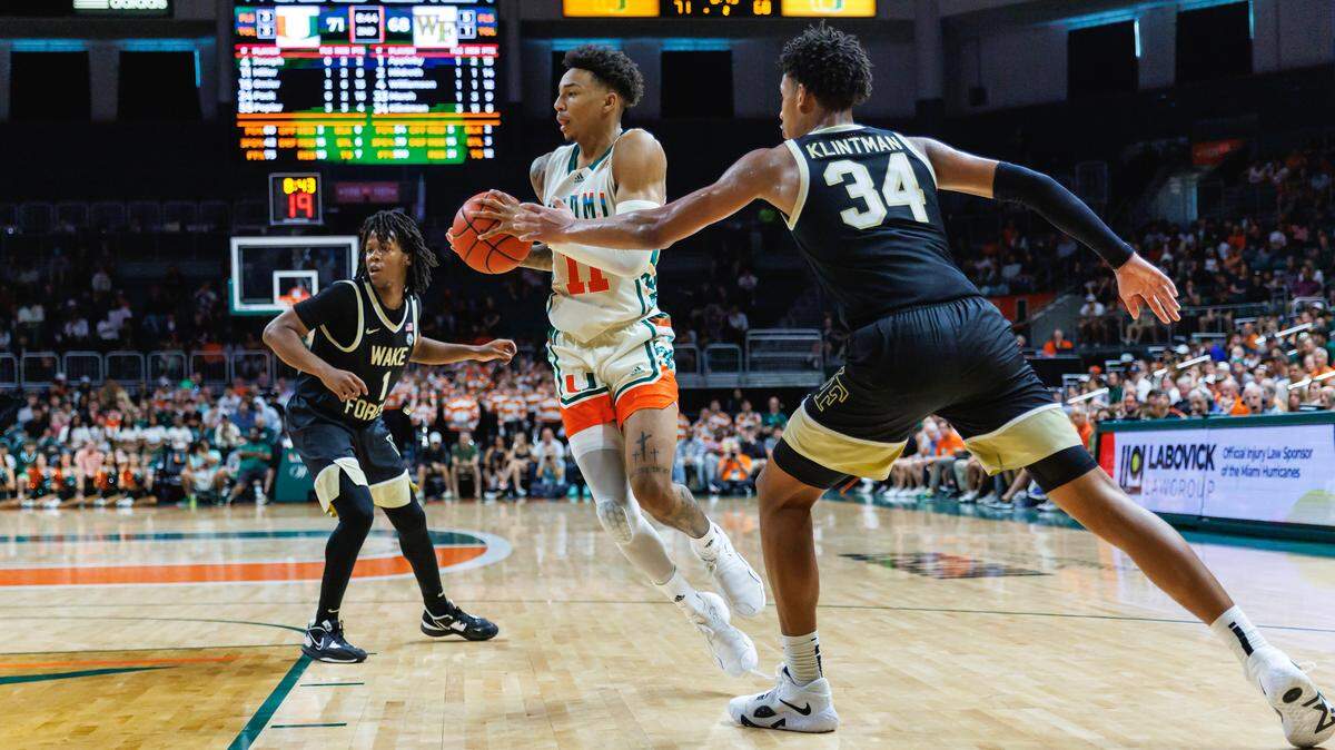 Miami Hurricanes guard Jordan Miller (11) drives against Wake Forest Demon Deacons guard Tyree Appleby (1) and Demon Deacons forward Bobi Klintman (34) during the second half of an NCAA college basketball game at Watsco Center on Saturday, February 18, 2023 in Coral Gables, Florida.