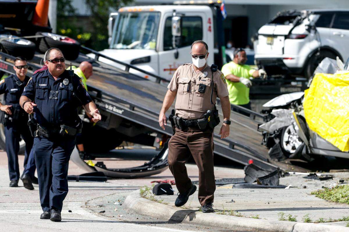 A Miami-Dade police officer, center, and a South Miami police officer, left, walk away from the scene where at least three people were killed and one taken to the hospital after a car crash in the intersection of Sunset Drive and Southwest 92nd Avenue on Tuesday, Aug. 31, 2021.