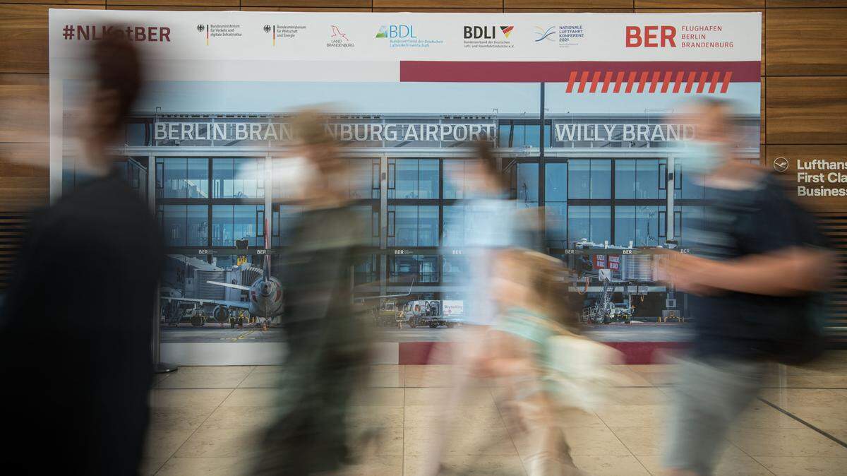 Passengers with face masks and suitcases walk in the BER Willy Brandt airport in Brandenburg, near Schoenefeld and Berlin, on July 28, 2021.