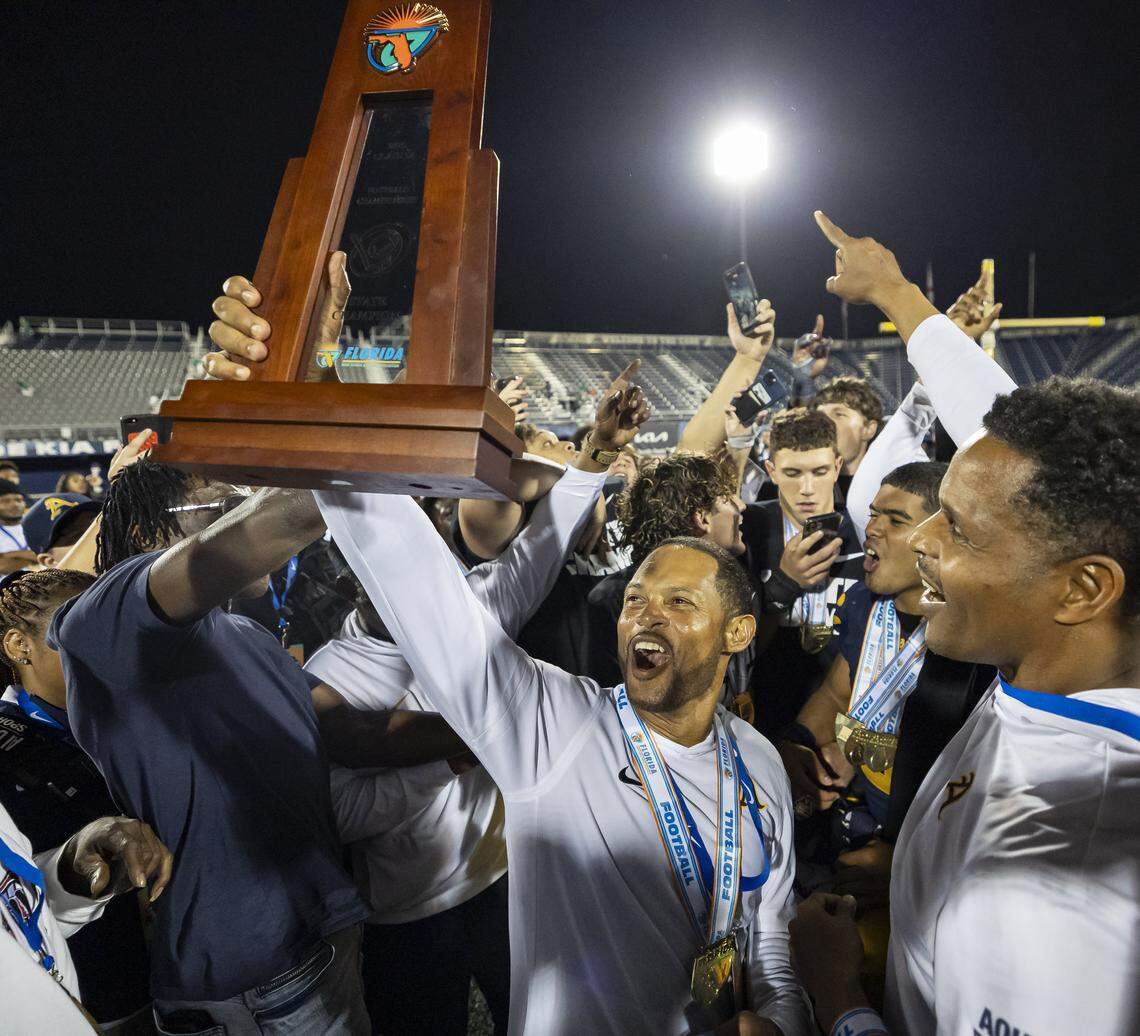 St. Thomas Aquinas Raiders head coach Roger Harriott lifts the trophy after defeating the Lakeland Dreadnaughts in their Class 5A state championship football game at Pitbull Stadium on Thursday, Dec. 11, 2025, in Miami, Fla.