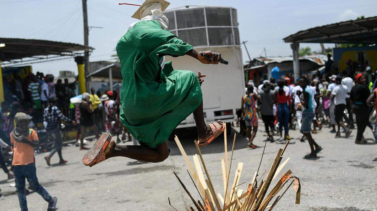 His face obscured, a man jumped over a bonfire on the street as members of a gang led by Jimmy Cherizier marched to demand justice for slain Haitian President Jovenel Moïse in the La Saline neighborhood of Port-au-Prince, Haiti, on Monday, July 26, 2021. Cherizier, alias Barbecue, is a former police officer who heads a gang coalition known as ‘G9 Family and Allies.’ Moïse was assassinated on July 7 at his home.