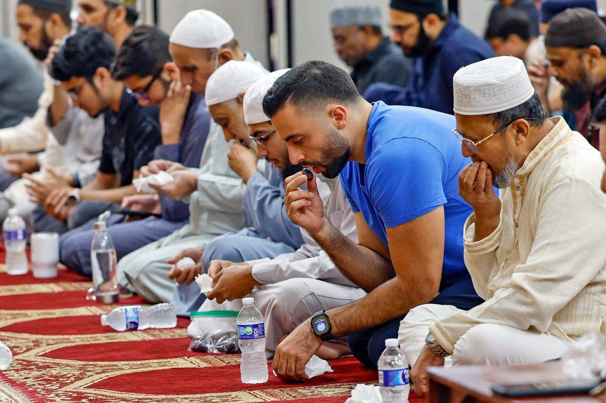 Abdallah Hasouneh, wearing a blue shirt, joins others as they end their fast on the Day of Arafah eating dates and drinking water.