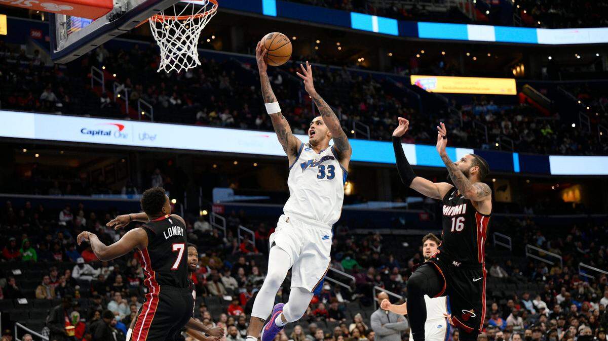 Washington Wizards forward Kyle Kuzma (33) goes to the basket against Miami Heat guard Kyle Lowry (7) and forward Caleb Martin (16) during the first half of an NBA basketball game Friday, Nov. 18, 2022, in Washington.