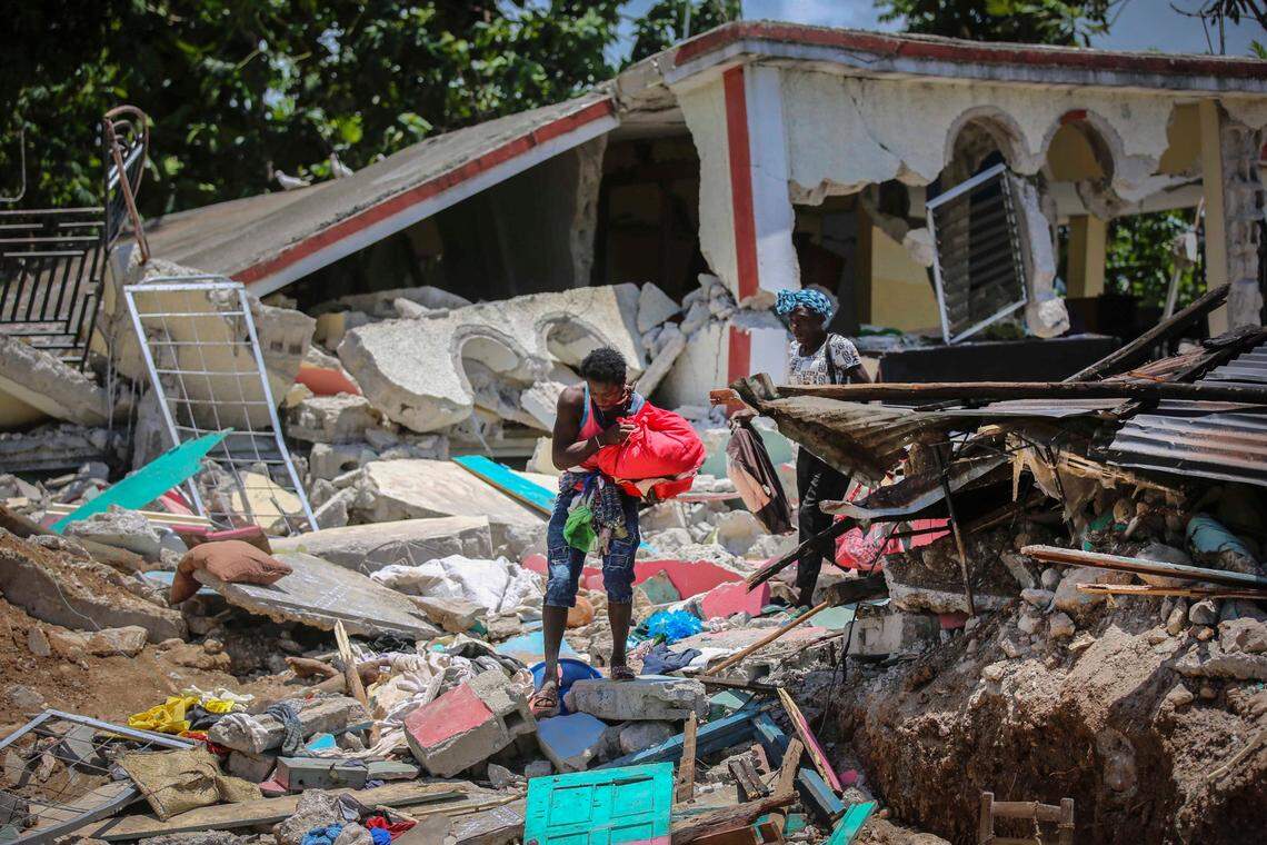Locals recover their belongings from their homes destroyed in the earthquake in Camp-Perrin, Les Cayes, Haiti, Sunday, Aug. 15, 2021. The death toll from the magnitude 7.2 earthquake in Haiti soared on Sunday as rescuers raced to find survivors amid the rubble ahead of a potential deluge from an approaching tropical storm.