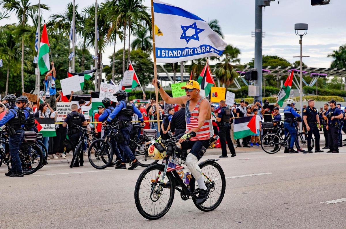 A pro-Israel protestor rides his bike along Biscayne Blvd. in front of a protest rally in support of Palestinians in Gaza during the conflict between Israel and Hamas at Bayfront Park in Miami on Friday, October 13, 2023.