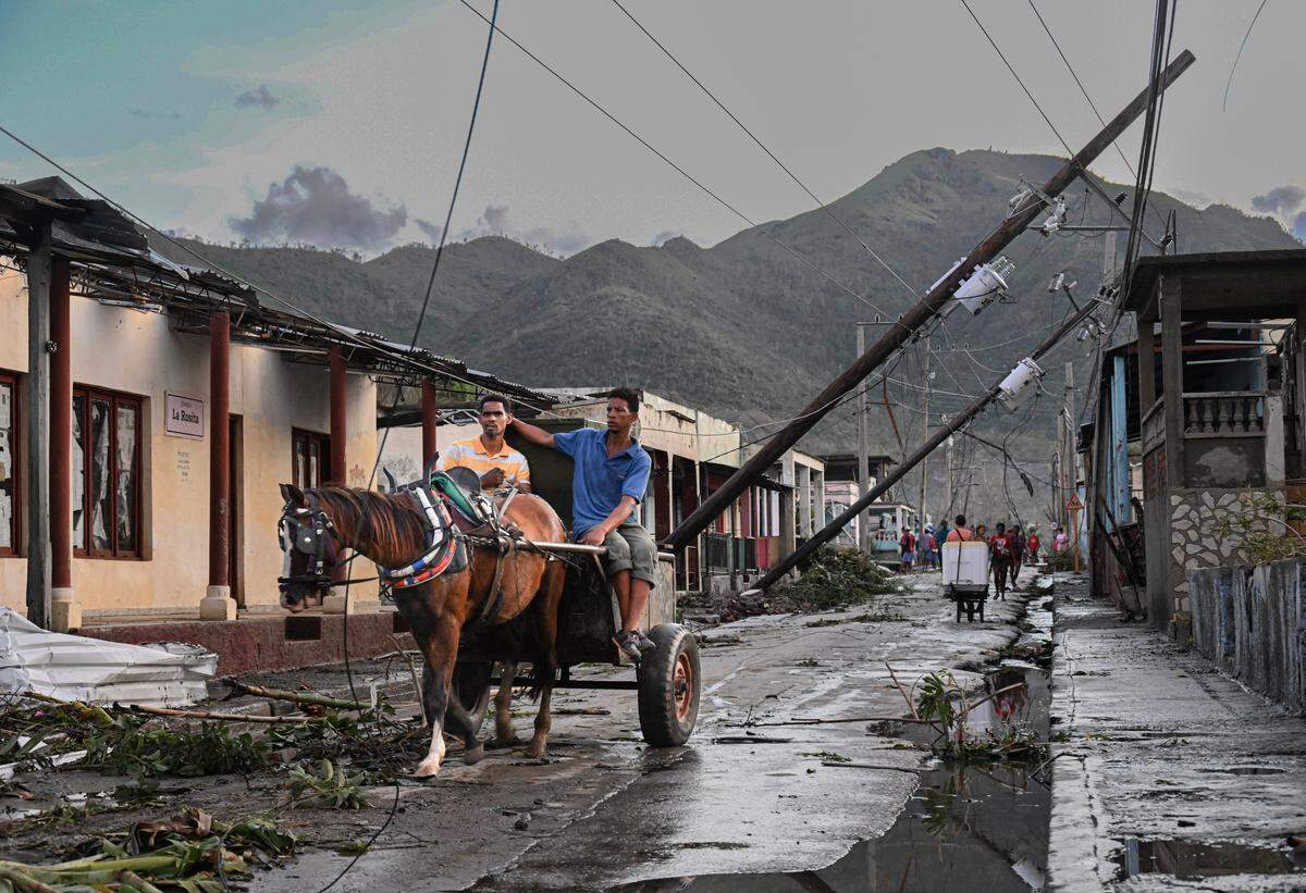 Residents of El Cobre, in the province of Santiago de Cuba, ride in a horse-pulled cart past downed power lines following the passage of Hurricane Melissa, on October 29, 2025. 