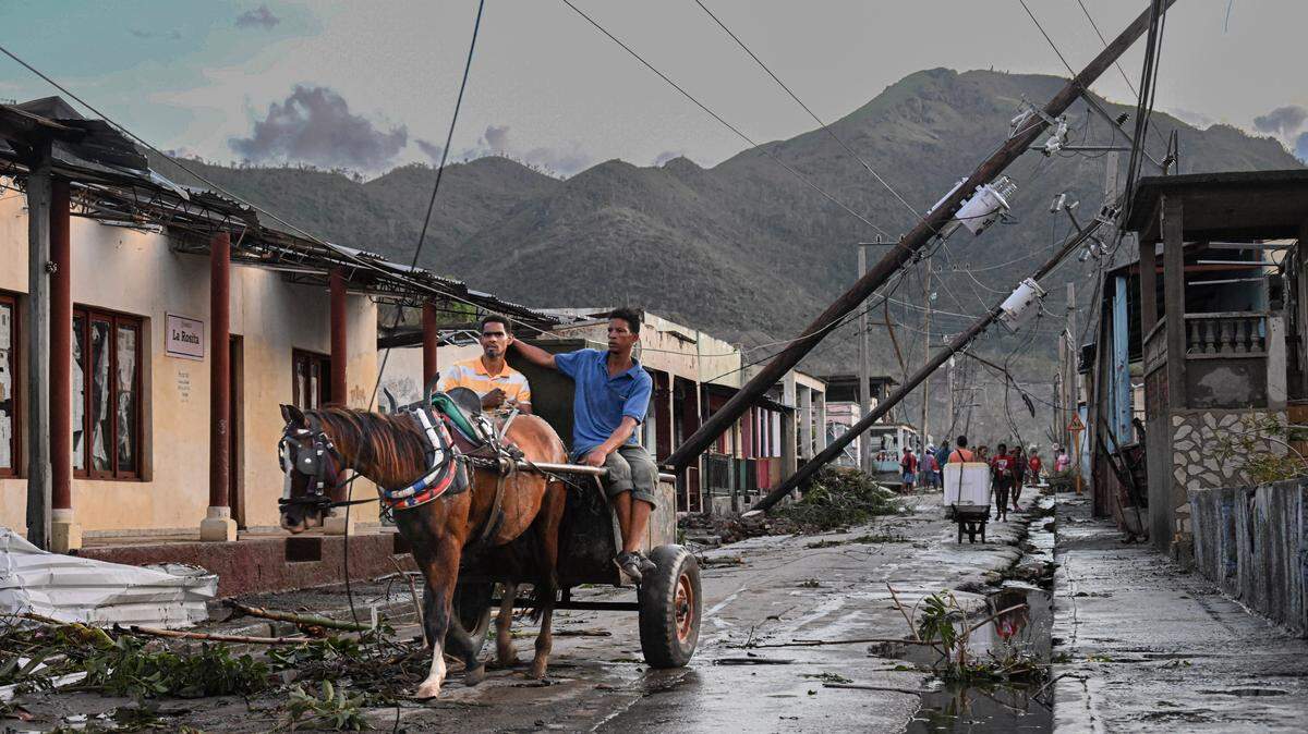 Residents of El Cobre, in the province of Santiago de Cuba, ride in a horse-pulled cart past downed power lines following the passage of Hurricane Melissa, on October 29, 2025. 