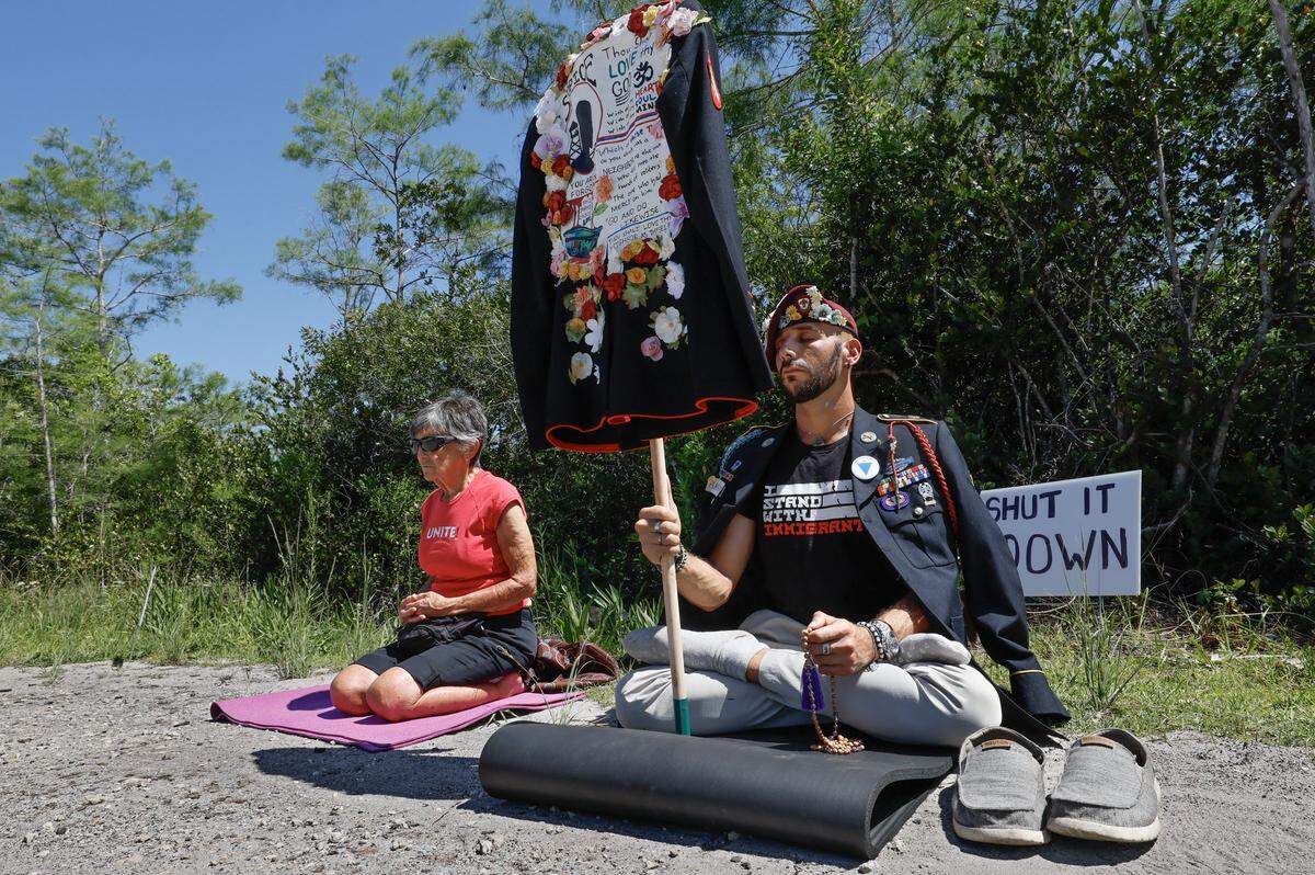 Javier Del Rio, who served in the US Army and Marines, prays for detainees along with Jean Erlbaum during a May Day Rally outside of Alligator Alcatraz located at the Dade-Collier Training and Transition Airport in the Florida Everglades, Ochopee, Florida, on Friday, May 1, 2026.