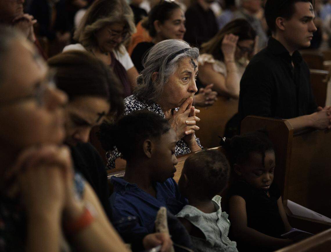 A woman prays after receiving ashes on her forehead during Ash Wednesday mass on Wednesday, Feb. 18, 2026, at Gesu Catholic Church in downtown Miami. The mass was fully packed with standing room only at the back of the church. 