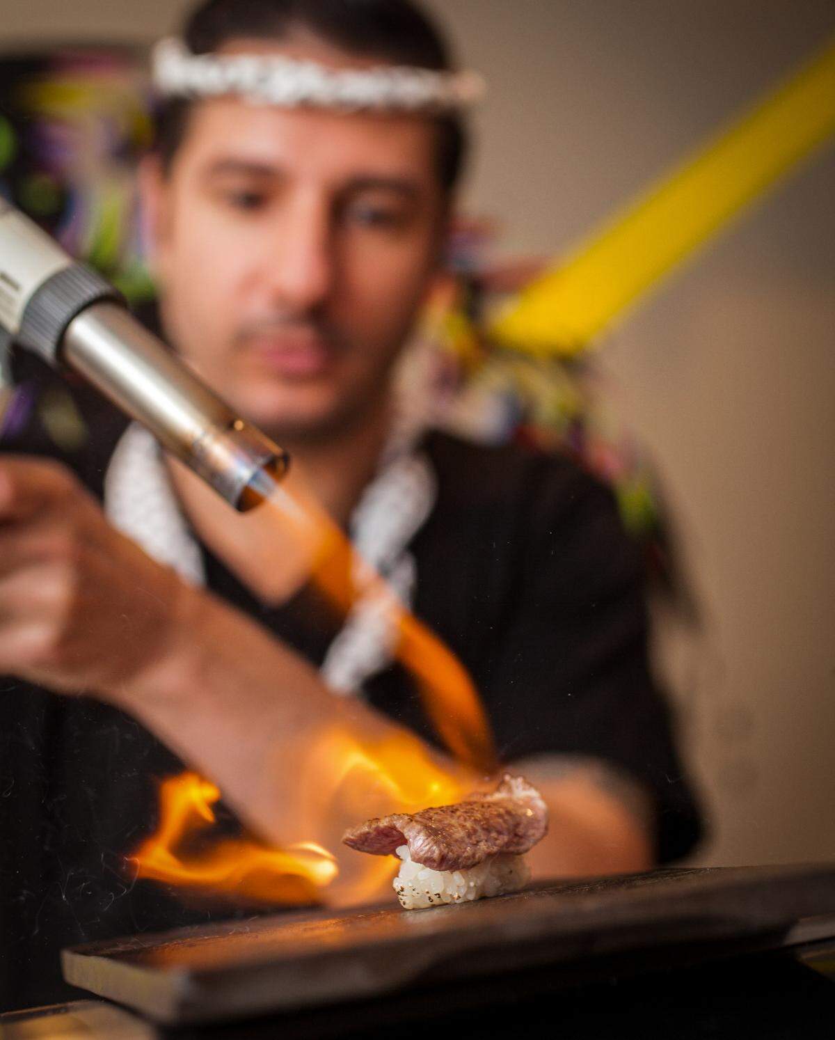 A chef uses a torch on a slice of waygu beef at Sushi by Bou, now open in Brickell.