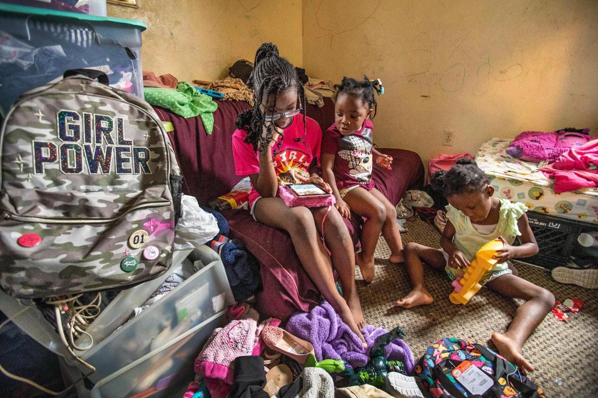 Oliviea, 10, watches a video on her smart device as Abigail, 3, joins in. Terylin, 5, plays with her Legos.
