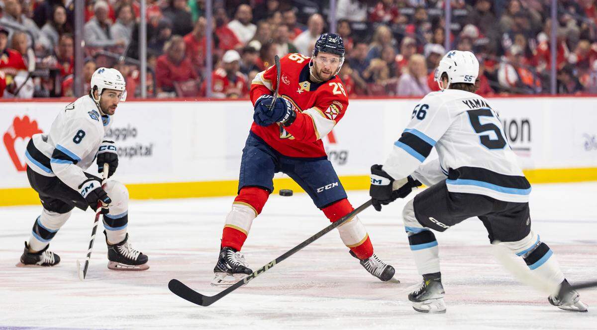 Florida Panthers defenseman Uvis Balinskis (26) shoots the puck as Utah Hockey Club right wing Kailer Yamamoto (56) defends in the first period of their NHL game at Amerant Bank Arena on Friday, March 28, 2025, in Sunrise, Fla.