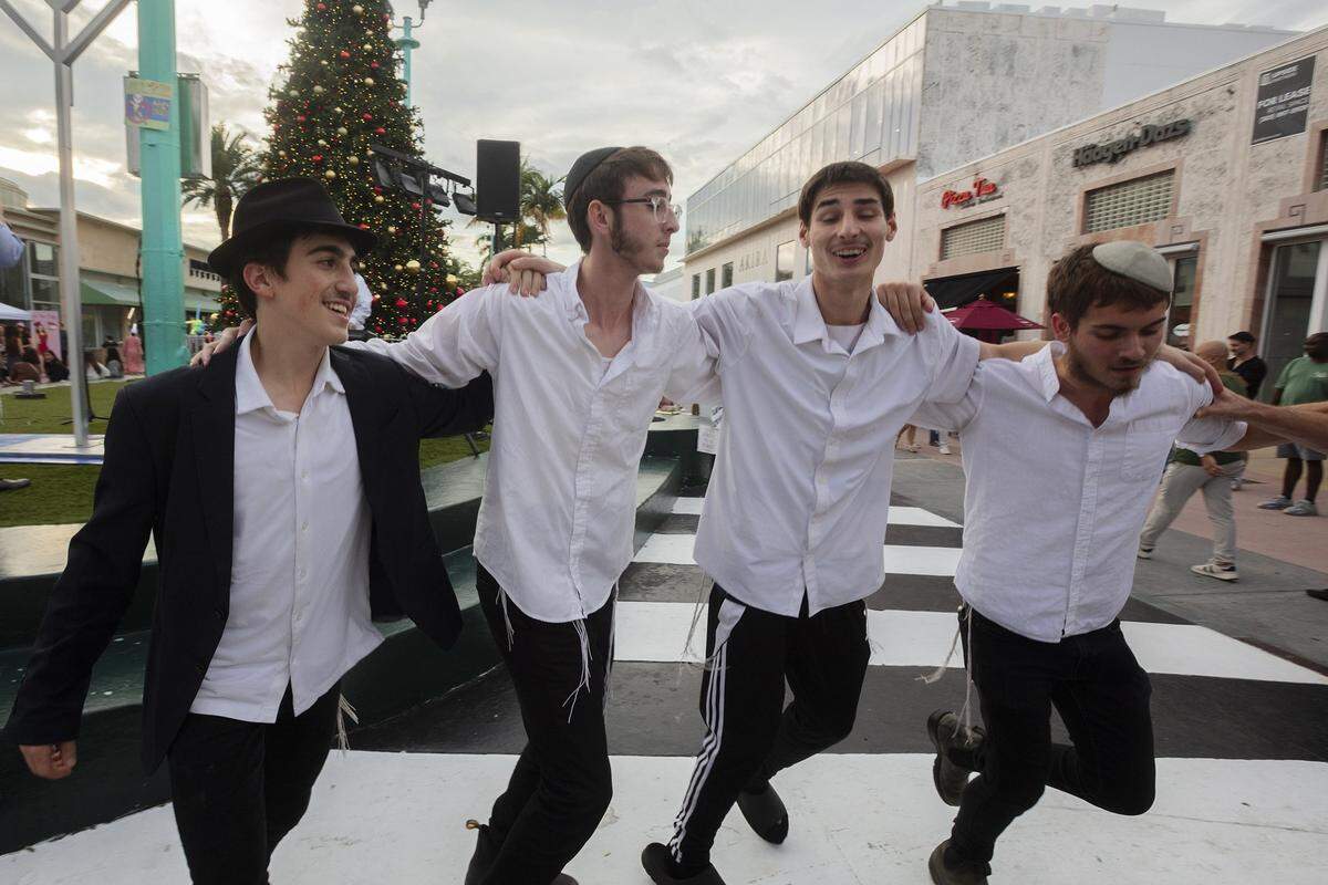 Shimmy Rubashkin, 15, from left, Yosef Novack, 18, Yakov Motorca, 17, and Dovie Givre, 19, dance during a Hanukkah festival marking the first night of Hanukkah on Lincoln Road in Miami Beach, Fla., on Dec. 14, 2025.
