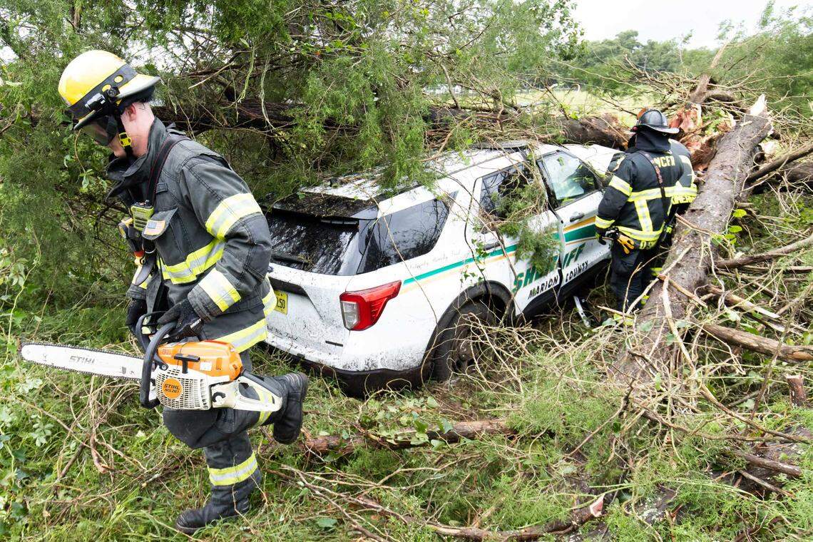 Marion County Fire Rescue Firefighter/EMT Jacob Knobbe, left carries a chain saw as Lt. Daniel Smith, center and Driver Engineer Matt Kimerling, right, clear out brush after responding to a single vehicle accident that involved Marion County Sheriff Deputy Jonathan Coleman Wednesday morning, August 30, 2023. The accident occurred in the 6300 block of NE 36th Ave Rd. In Ocala, Fla. The deputy was transported from the scene with a possible broken ankle and some cuts an abrasions according to Marion County Chief Deputy Robert Douglas. The accident occurred as Hurricane Idalia passed through Marion County. [Doug Engle/Ocala Star Banner]2023