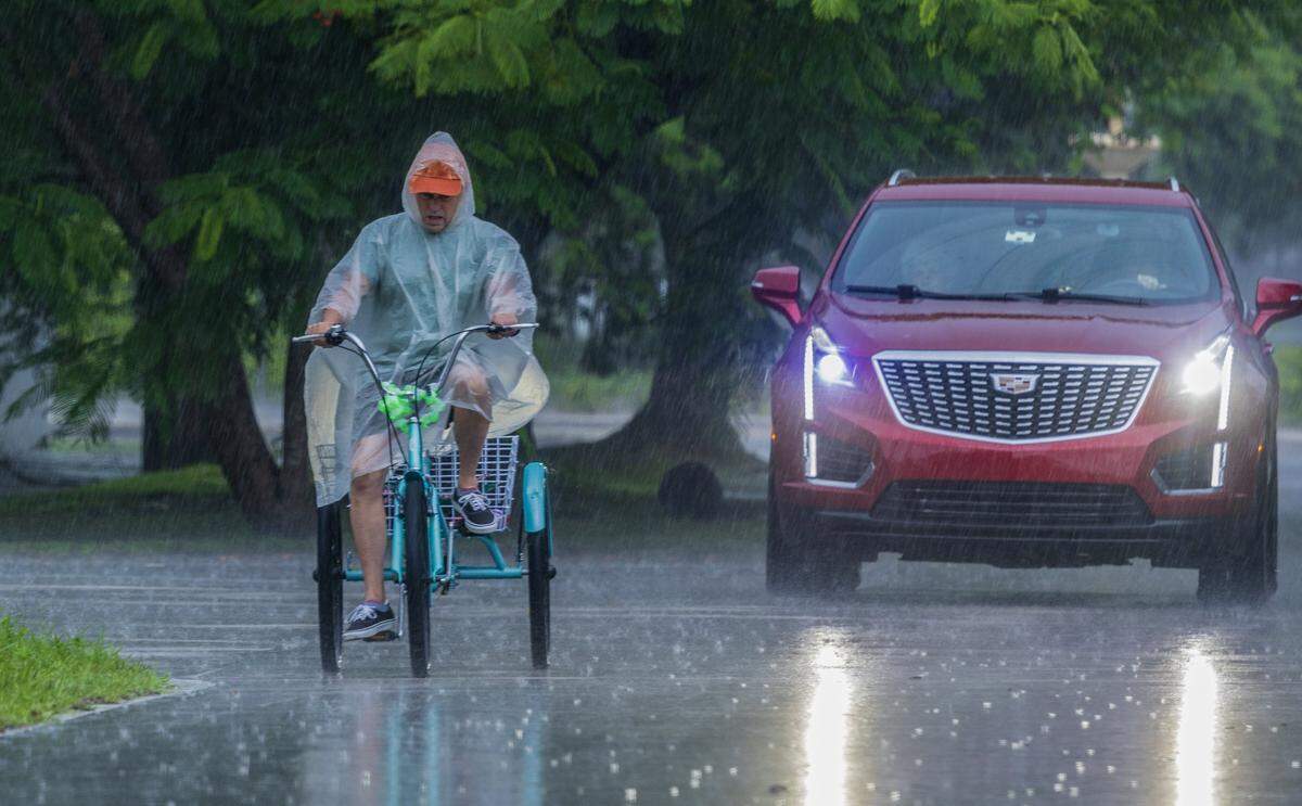 A tricyclist endures the rain on a Miami street on Tuesday afternoon.