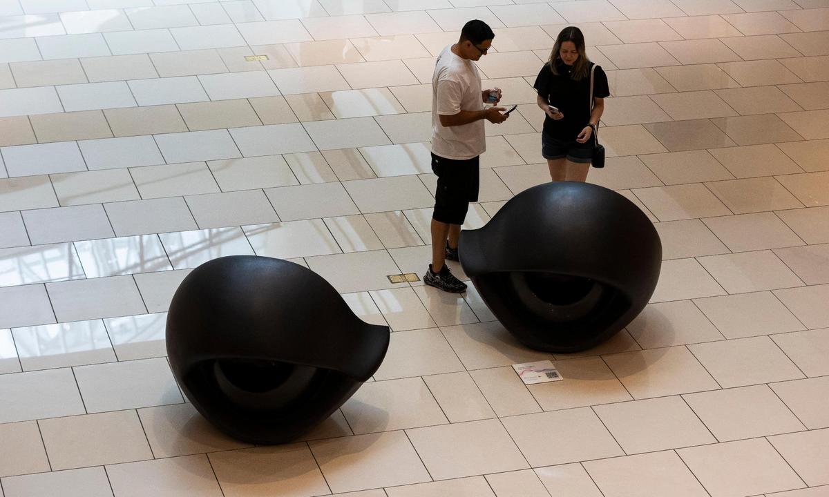 People stand next to ‘Eye Benches,’ a sculpture by Louise Bourgeois, on Sept. 25, 2024. The late artist’s work is one of the recent art installations available for visitors to see at Aventura Mall.