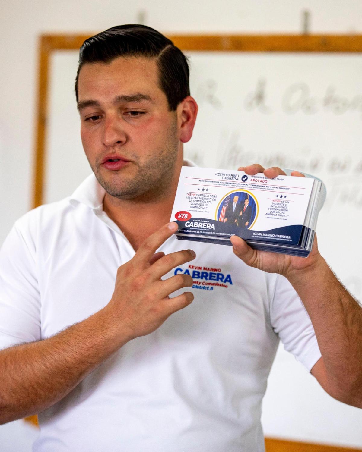 Dist. 6 Miami-Dade Commission candidate Kevin Marino Cabrera points to a campaign brochure featuring former President Donald Trump at a Cabrera campaign event on Wed., Oct. 12, 2022.