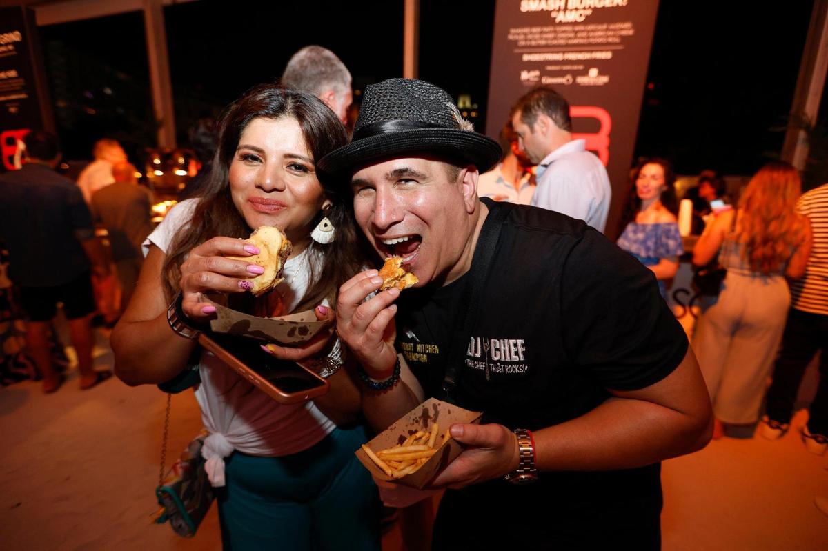 Sonia Weiss and DJ Chef Marc Weiss try out the burgers during the Burger Bash at the South Beach Wine & Food Festival on the sand by the Ritz Carlton in Miami Beach, Florida on Thursday, February 23, 2023.