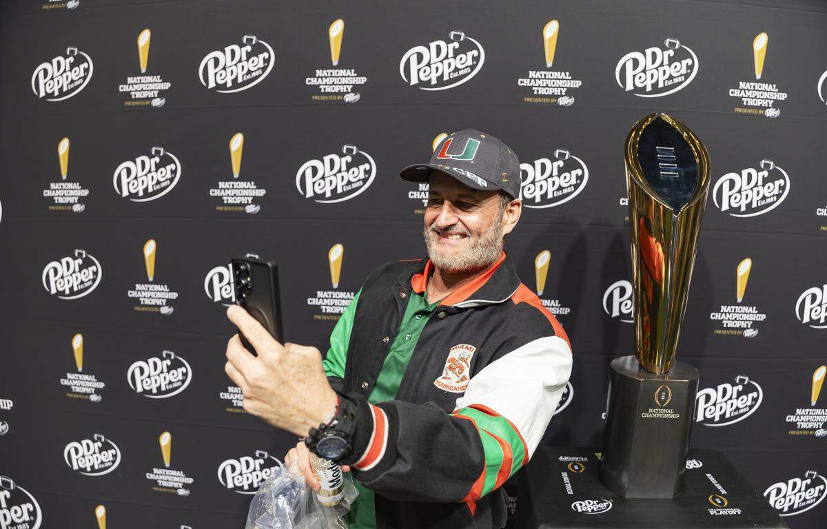 Gaspar Torres takes a selfie with the national championship trophy while visiting the Playoff Fan Central at the Miami Beach Convention Center on Friday, Jan. 16, 2025.