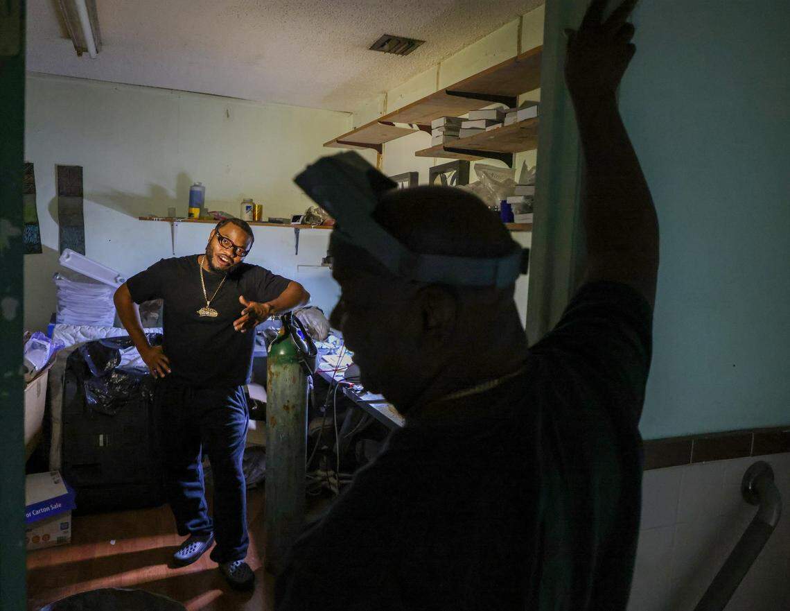 Phillip “Philo” Norville, left, is learning the business from his father, Lando Plein, right, who creates custom gold teeth and grillz at his shop, Lando Golds. 