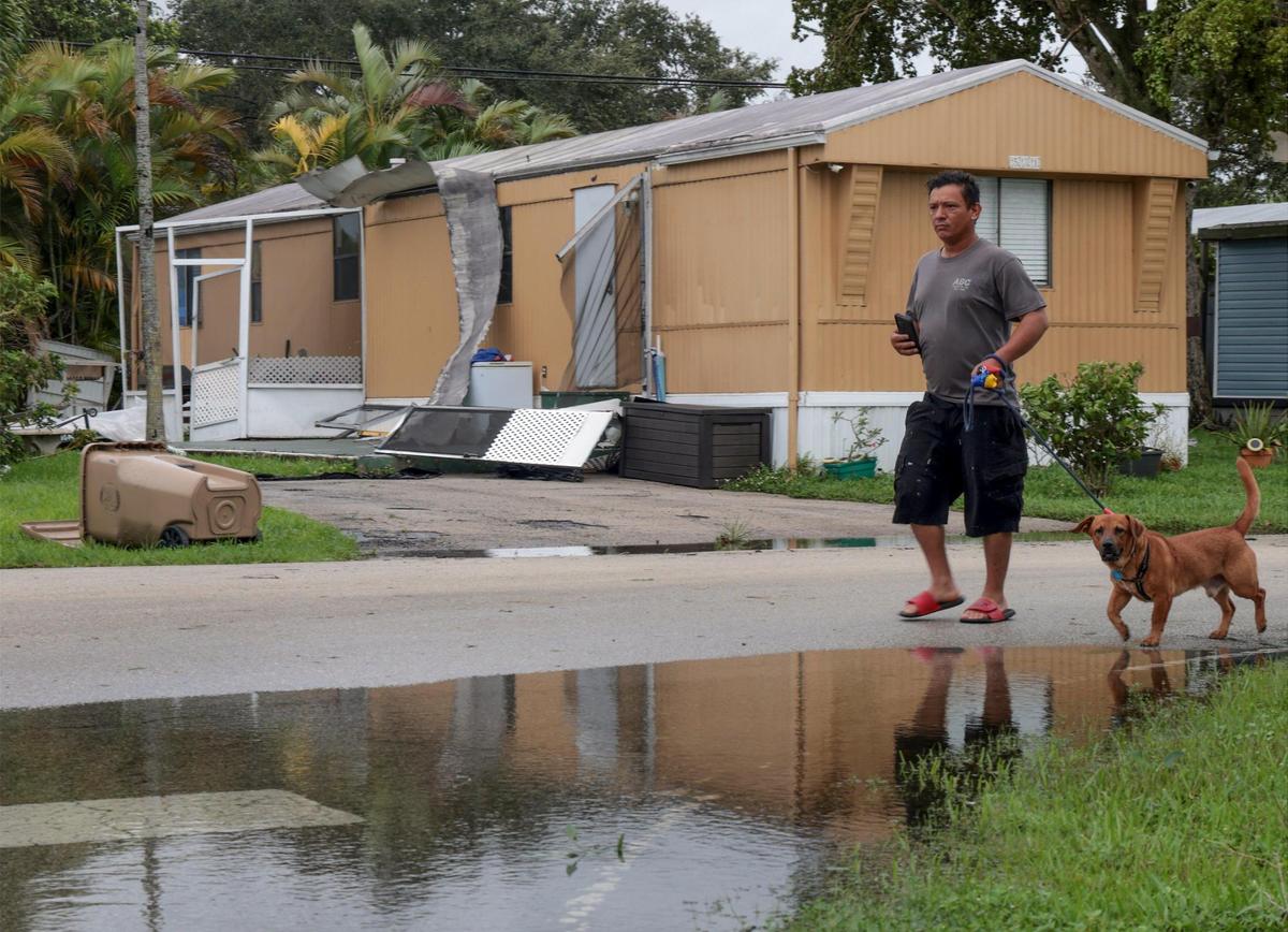 Curious resident walks her dog while surveying the damage cause by the early morning tornado. A tornado possibly spawned by Hurricane Ian caused downed trees, traffic lights, and damage to property in and around Sunshine Village, a mobile home park in Davie, Florida on Wednesday, September 28, 2022.