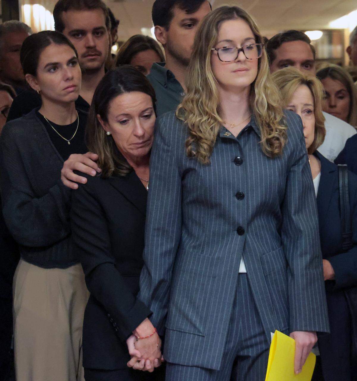 Surrounded by family, friends, and supporters, Cecilia Pino, center, the wife of developer George Pino, holds the hand of her daughter, Carolina Pino, right, as Pino’s attorney gives a brief statement in the hallway near Courtroom 4-3 at the Richard E. Gerstein Justice Building on Thursday, November 21, 2024, in Miami, Florida.