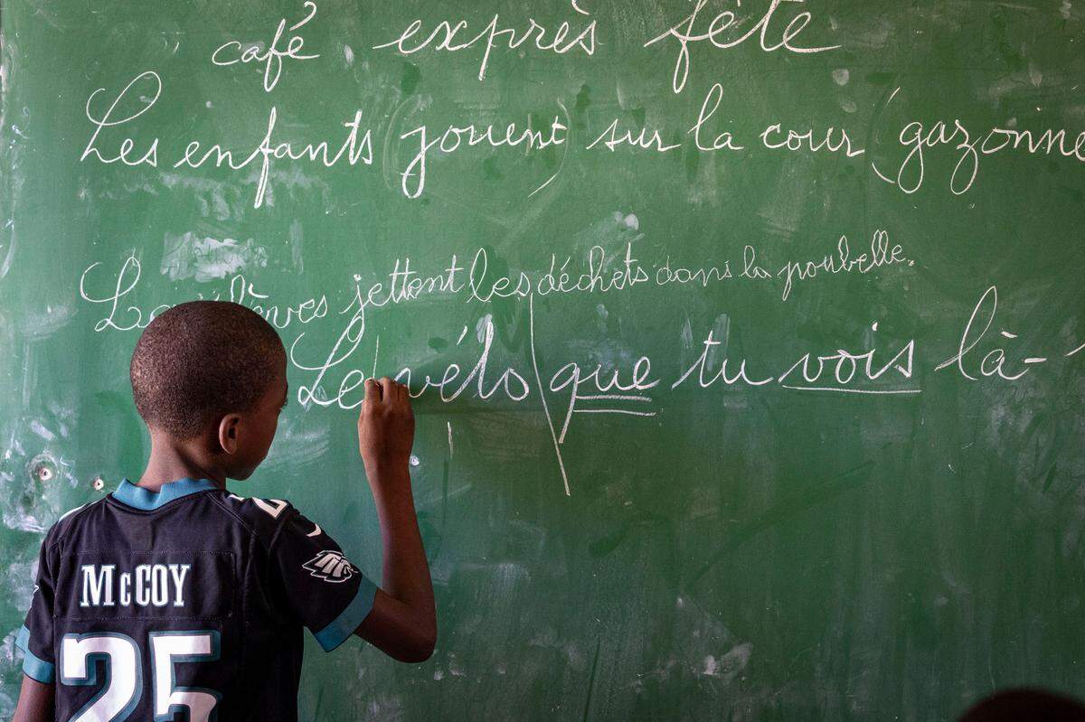A boy works on the chalkboard in front of class during summer classes at Ecole National Louis Borno de Léogâne in Léogâne, Haiti.