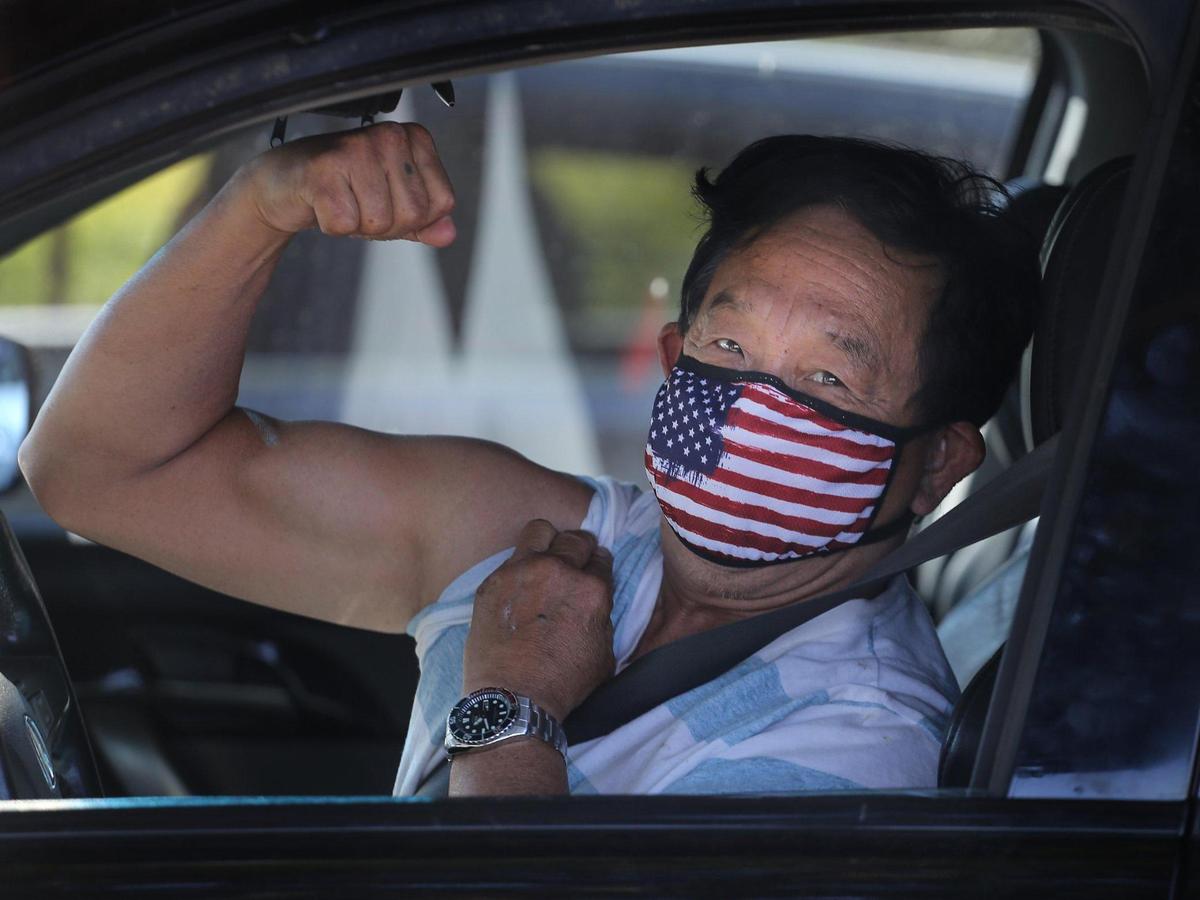 A driver flexes his arm as he and others wait in line to receive his vaccination shot on Sunday, January 10, 2021, as the Florida Division of Emergency Management, in partnership with Senator Shevrin Jones, hosted a COVID-19 vaccination event for seniors 65 and older to increase immunity and protect the health of South Florida’s most vulnerable residents at the Koinopnia Worship Center and Village in Pembroke Park, Florida.