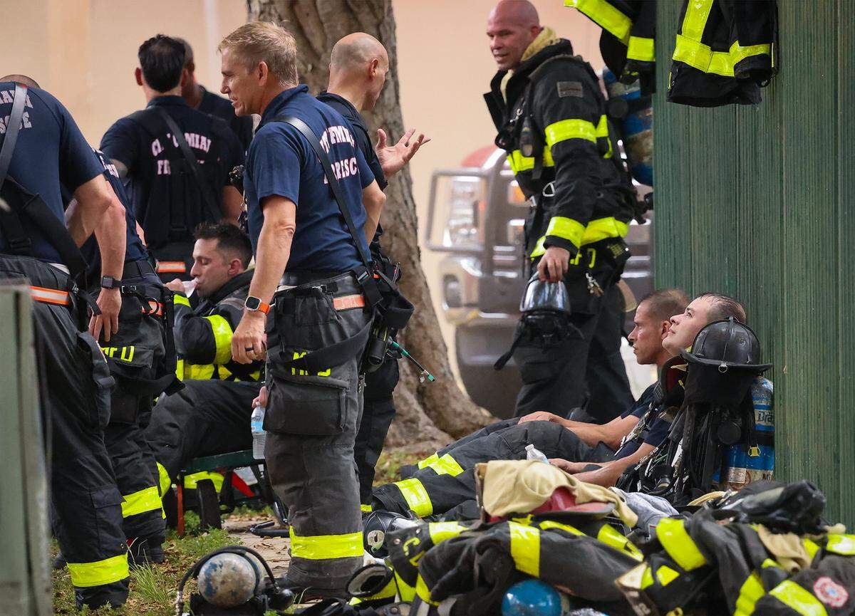 City of Miami Fire & Rescue firefighters take a short break while others suit up to continue to battle a fire that preceded reports of a shooting inside the Temple Court Apartments shortly after 8:15 a.m. on Monday, June 10, 2024, in Miami, Florida. This photo was part of a package that won second place in the Florida Society of News Editors Spot News Photography category.