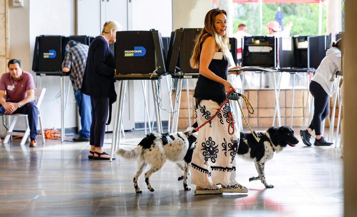 Eva Moore carries her voting ballot with her service dogs Apollo and Vinkenoog at the Coral Gables Country Club, where precincts 601 and 608 are located, during Election Day in Coral Gables, Florida on Tuesday, November 5, 2024.