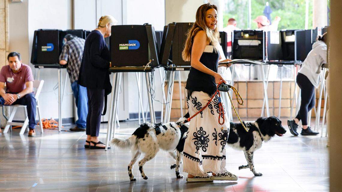 Eva Moore carries her voting ballot with her service dogs Apollo and Vinkenoog at the Coral Gables Country Club, where precincts 601 and 608 are located, during Election Day in Coral Gables, Florida on Tuesday, November 5, 2024.