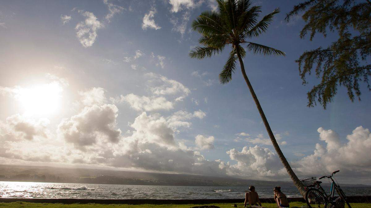 In this Aug. 30, 2015, photo, Keenin Ide, left, of Hilo, Hawaii, and Medea Yankova, of Sofia, Bulgaria, sit near Hilo Bay in Hilo, Hawaii. Hawaii’s recent blizzard warning is a first in over three years, but is not rare because it can snow on mountain peaks.
