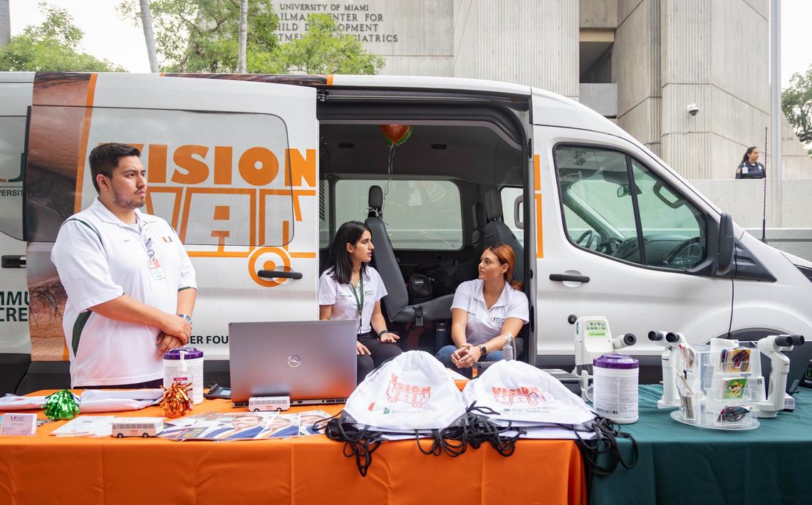 Kevin Zagoya, left, Nada Fareed, center, and Emilie Mikhail work at the UM Vision Van table during the naming ceremony of the UHealth Jackson Metro Station, formerly known as the Civic Center Station, on Friday, July 12, 2024 in Miami, Fla.