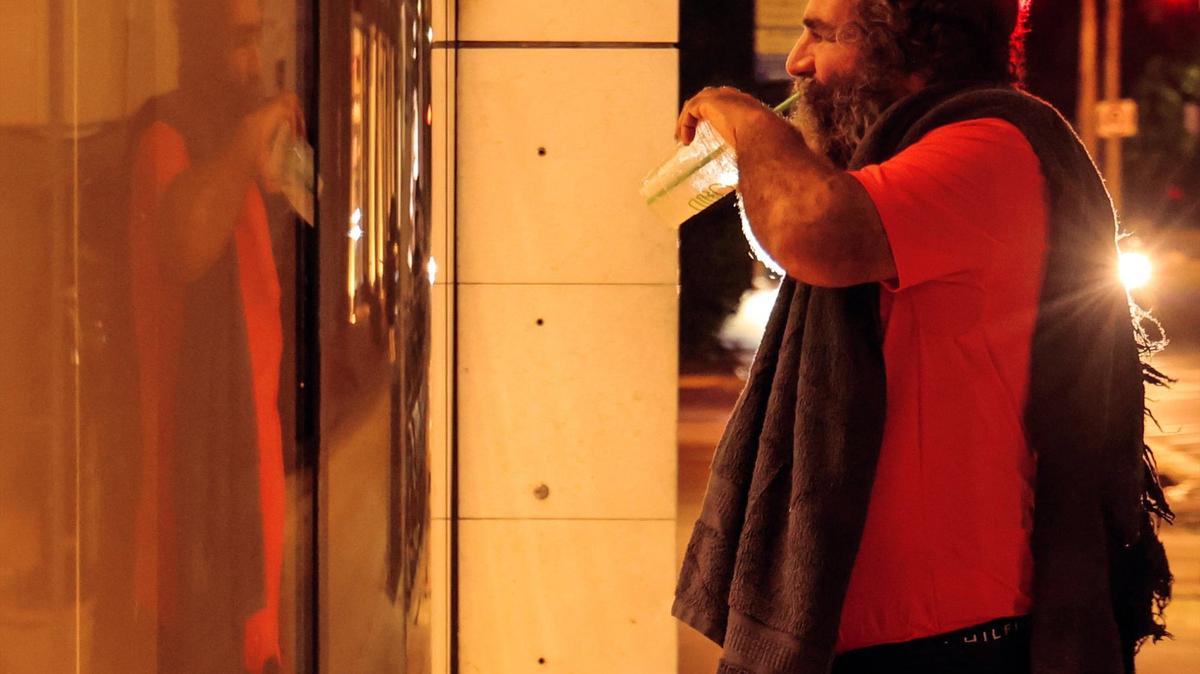 An unsheltered man gazes at one of the storefronts on Lincoln Road on Aug. 22 in Miami Beach. On Wednesday, the city commission voted to rescind a local tax referendum to help fund the Miami-Dade Homeless Trust.