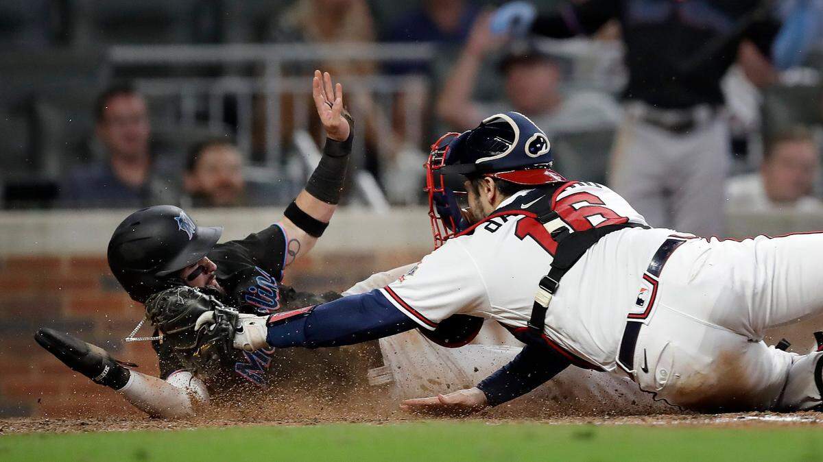 Miami Marlins’ Eddy Alvarez, left, slides safe to score past the tag of Atlanta Braves catcher Travis d’Arnaud in the ninth inning of a baseball game Saturday, Sept. 11, 2021, in Atlanta.