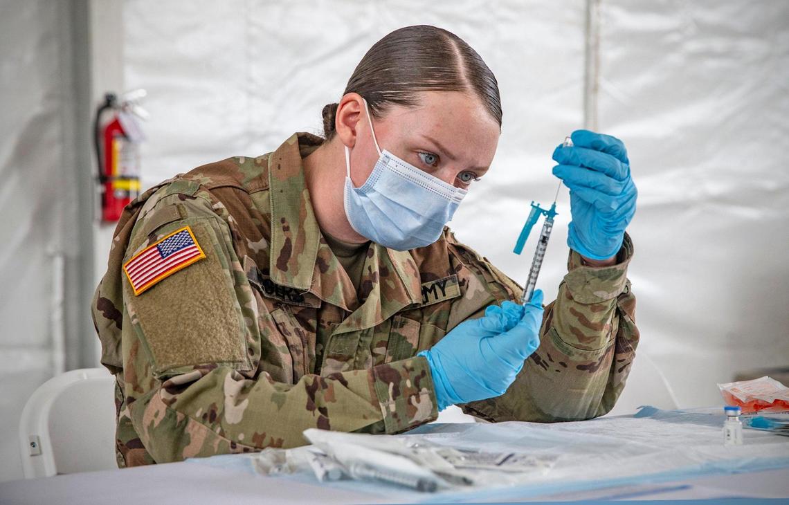 U.S. Army Medic Kristen Rogers prepares a COVID-19 needle for injection during opening day at the FEMA vaccination site on Miami Dade College’s North Campus on Wednesday, March 3, 2021.