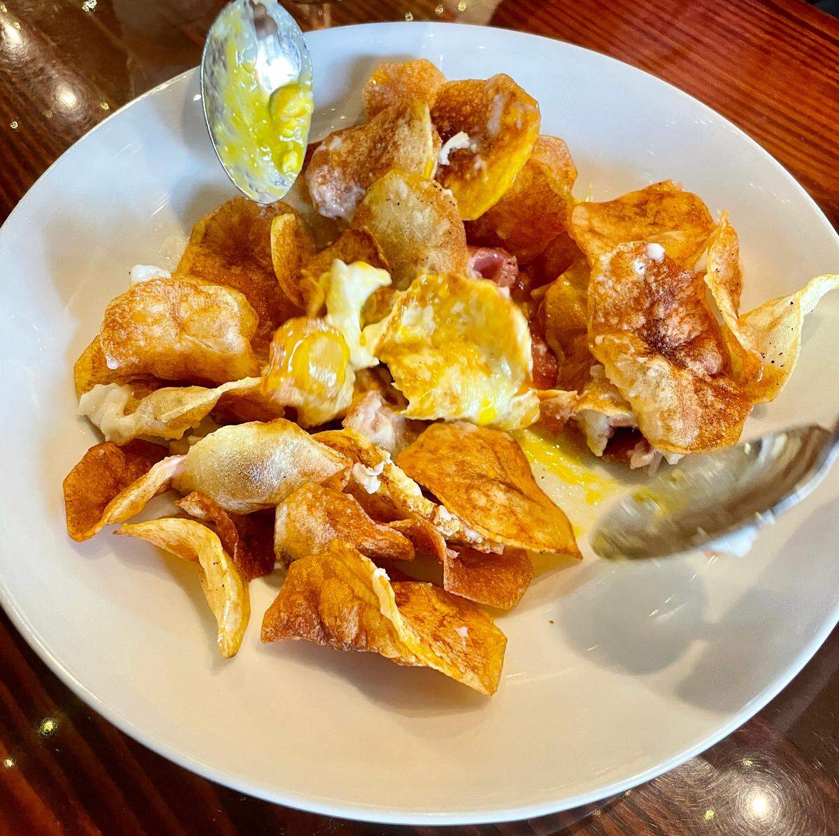 Huevos Rotos are housemade potato chips with serrano ham and a soft egg.