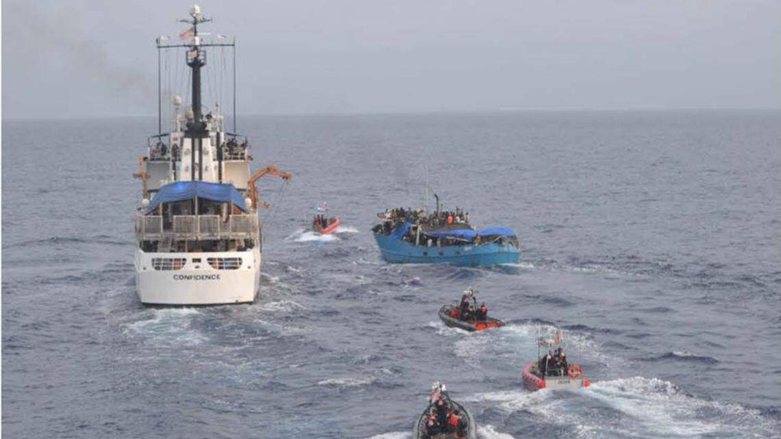 An overloaded migrant vessel sails next to the U.S. Coast Guard Cutter Confidence off the northwest coast of Haiti on Thursday, May 20, 2022. The Coast Guard said the boat collided with the bow of the cutter.