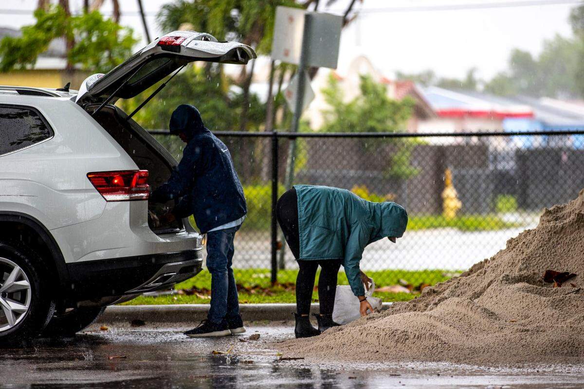 Miami-Dade County residents Jaquelyn Andreu, 28, right, and her father-in-law Frank Andreu, 61, left, pack sand into plastic bags as they prepare for potential flooding at Grapeland Heights Park in Miami, Florida, on Friday, June 3, 2022.