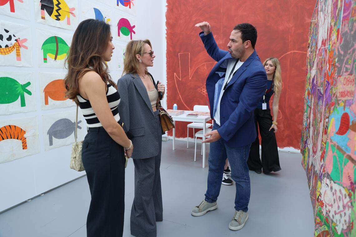Miami Beach, FL, December 2, 2025 -Untitled Art attendees inquire about Camilo Restrepo's pieces during a visit to La Cometa booth at the Untitled Art.