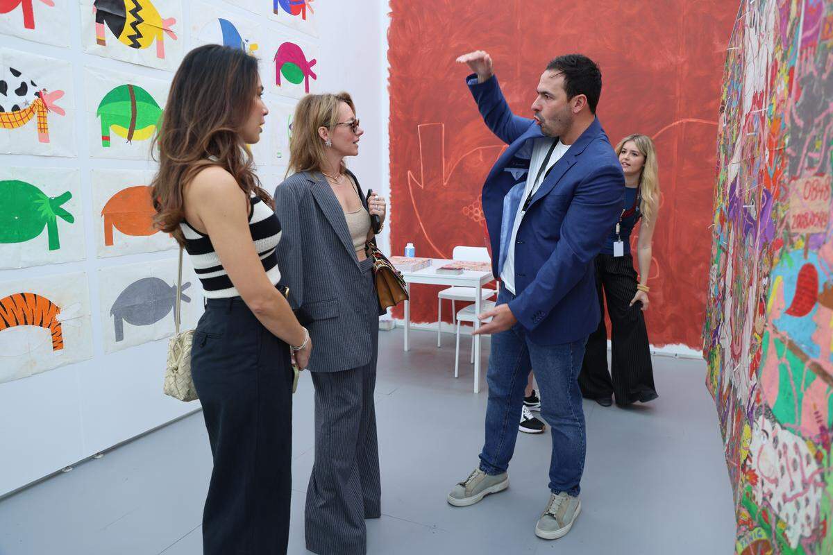 Miami Beach, FL, December 2, 2025 -Untitled Art  attendees inquire about Camilo Restrepo's pieces during a visit to La Cometa booth at the Untitled Art.