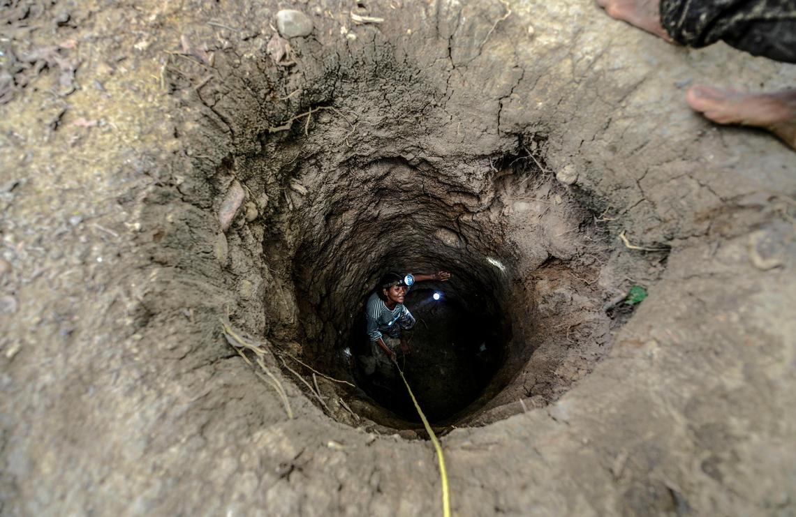 In El Callao, Bolívar state, a worker descends into a hole along a riverbank. It is a hazardous existence, compounded by the use of toxic mercury to separate gold from plain rock.