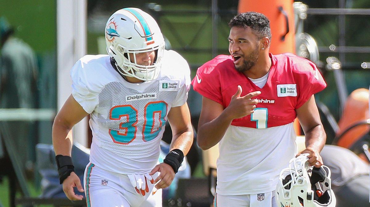 Miami Dolphins quarterback Tua Tagovailoa (1) talks with fullback Alec Ingold (30) as the run onto the field for practice at Baptist Health Training Complex in Miami Gardens on Wednesday, August 17, 2022.